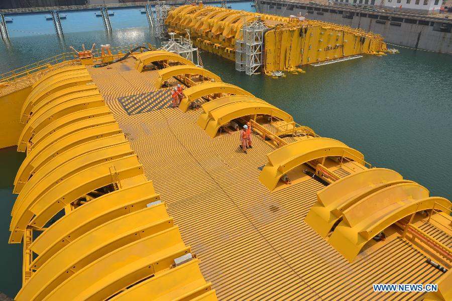 Wokers check newly-built deep-sea engineering equipment in Qingdao, east China's Shandong Province, July 3, 2013. With four sets of buoys and 16 sets of foundations, the deep-sea engineering equipment, the world's largest of this kind, was built and delivered by Wuchang Shipbuilding Industry Co., Ltd. to Petrobras as part of the Sapinhoa-Lula NE BSR Buoys & Foundations Project, which will be installed in an offshore oilfield in Brazil to work for a period of 27 years. The equipment is able to fit in deeper and more complicated marine environment and has extensively enlarged the scope of offshore oil exploitation, said Victor Bomfim, senior vice president of the project contractor Subsea 7 S.A. (Xinhua/Wan Houde)