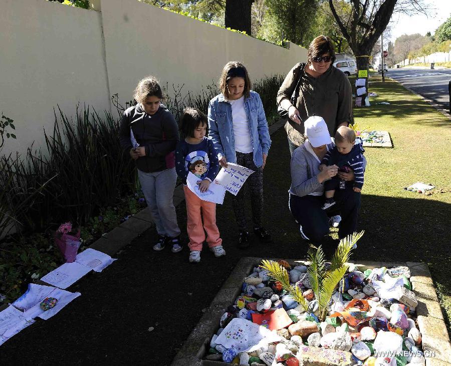 People present their wishing cards to South African former president Nelson Mandela outside Mandela's house in Johannesburg, South Africa, on July 3, 2013. Mandela is breathing by medical life support measures under the condition described as "perilous" by family members in a court paper-work released on Wednesday. (Xinhua/Li Qihua)