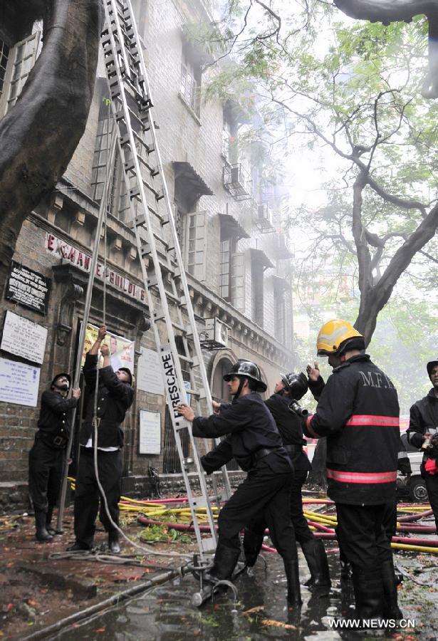 Firefighters set ladders to put out a fire caused by short circuit in Ballard Pier Estate Exchange building, Mumbai, India, on July 3, 2013. The big fire, which broke out on Wednesday morning in a government building in south Mumbai, is under control. (Xinhua/Wang Ping)