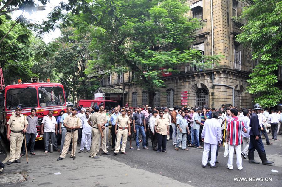 Police and residents gather near the scene of fire in Ballard Pier Estate Exchange building, Mumbai, India, on July 3, 2013. The big fire, which broke out on Wednesday morning in a government building in south Mumbai, is under control. (Xinhua/Wang Ping)