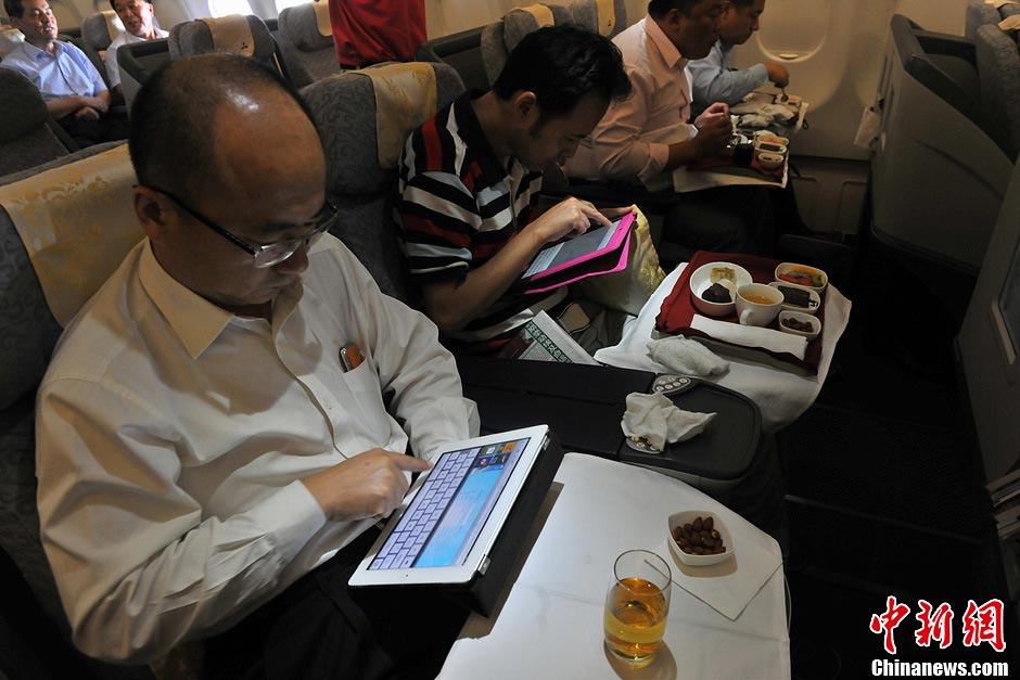 Passengers use tablet PCs to surf the Internet aboard Air China's flight CA4108 from Beijing to southwest China's Chengdu on July 3, 2013. (Photo/CNS)