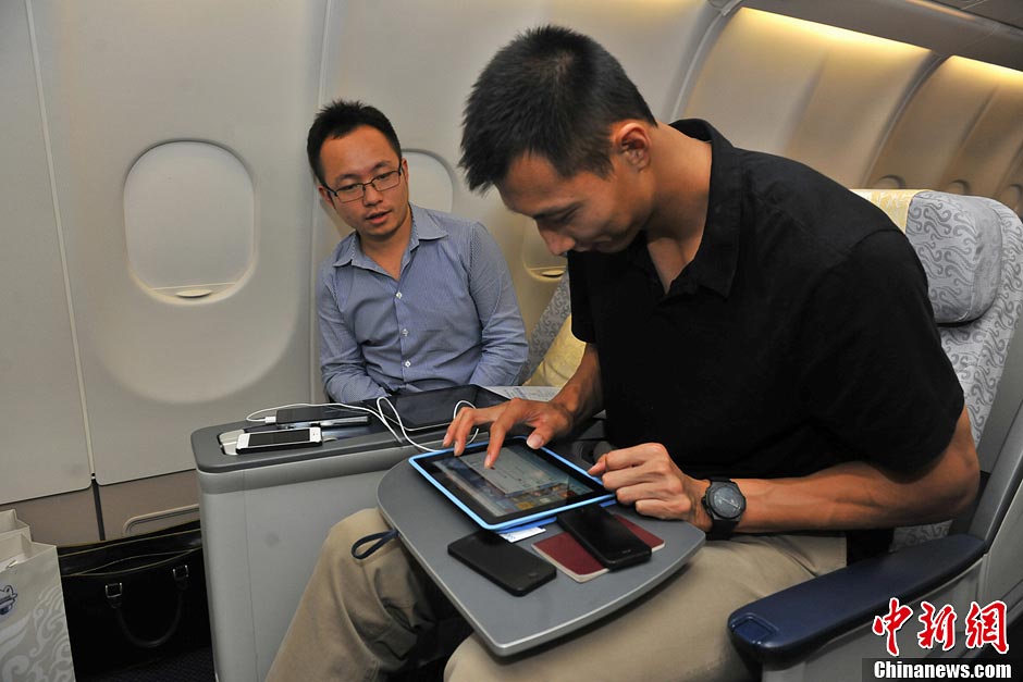 Yi Jianlian, a famous basketball player, surf the Internet aboard Air China's flight CA4108 from Beijing to southwest China's Chengdu on July 3, 2013. (Photo/CNS)