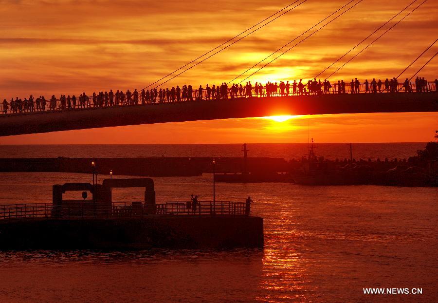 Visitors stand on a bridge to enjoy the scenery of sunset in Danshui, Xinbei, southeast China's Taiwan, July 3, 2013. Dubbed as the "Oriental Venice", Danshui is a pop scenery spot for tourists. (Xinhua/Tao Ming)