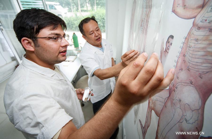 Mubeen Abdul (L), a student from Pakistan, learns skills of traditional Chinese medicine in a Chinese medicine clinic in Nantong, east China's Jiangsu Province, June 29, 2013. Mubeen is a fresh graduate seeking for a job in Nantong from Nantong University, majoring in clinical medicine. He has rented a house and attended many job fairs in a month. No answer from employers and low income from part-time job exerted much pressure on him. Finally he got a job for reception of foreign guests and management in Nantong First People's Hospital on July 1, 2013. "I love China and I will continue studying for master's degree and qualification of medical practitioners," said Mubeen. (Xinhua/Huang Zhe)
