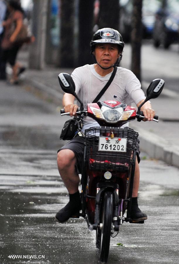 A citizen rides in the rain in Beijing, capital of China, July 4, 2013. Beijing witnessed a shower at the dusk on Thursday. (Xinhua/Chen Yehua)