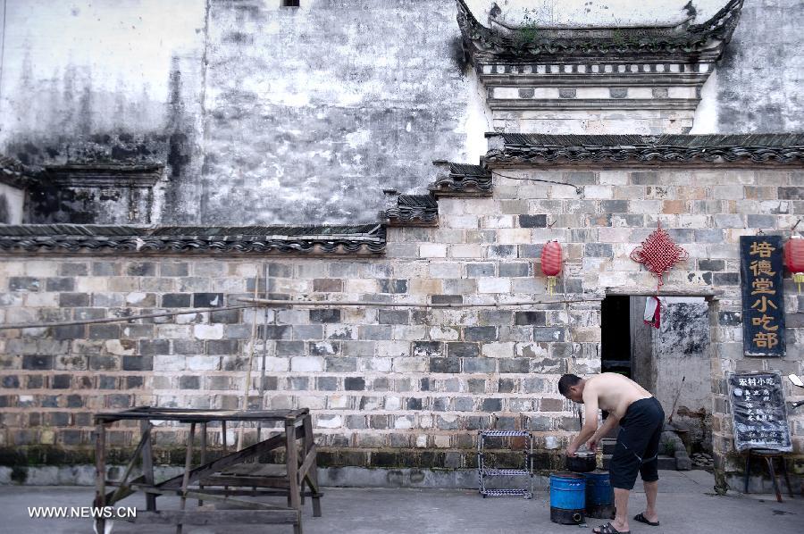 A local resident prepares to open his snack shop at Hongcun, an ancient village founded in 1131 in Huangshan City, east China's Anhui Province, early July 3, 2013. Listed as a world cultural heritage site, the village preserved to a remarkable extent the surviving examples of Anhui-style architecture and traditional lifestyle. (Xinhua/Guo Chen) 