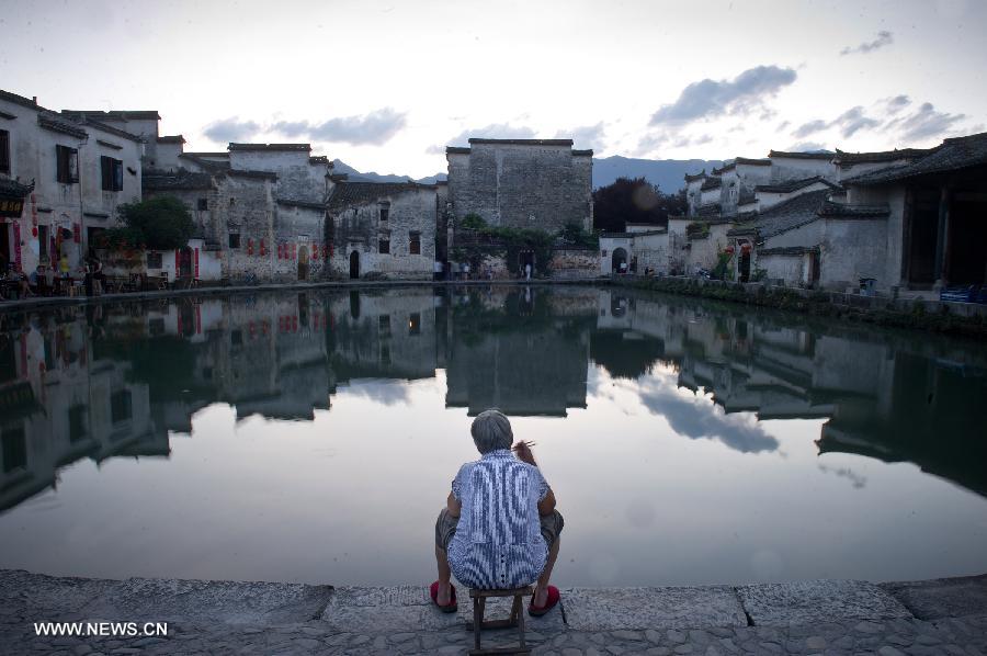 A local resident takes her supper by the side of the Yuezhao, or Moon Pool, at Hongcun, an ancient village founded in 1131 in Huangshan City, east China's Anhui Province, July 3, 2013. Listed as a world cultural heritage site, the village preserved to a remarkable extent the surviving examples of Anhui-style architecture and traditional lifestyle. (Xinhua/Guo Chen)