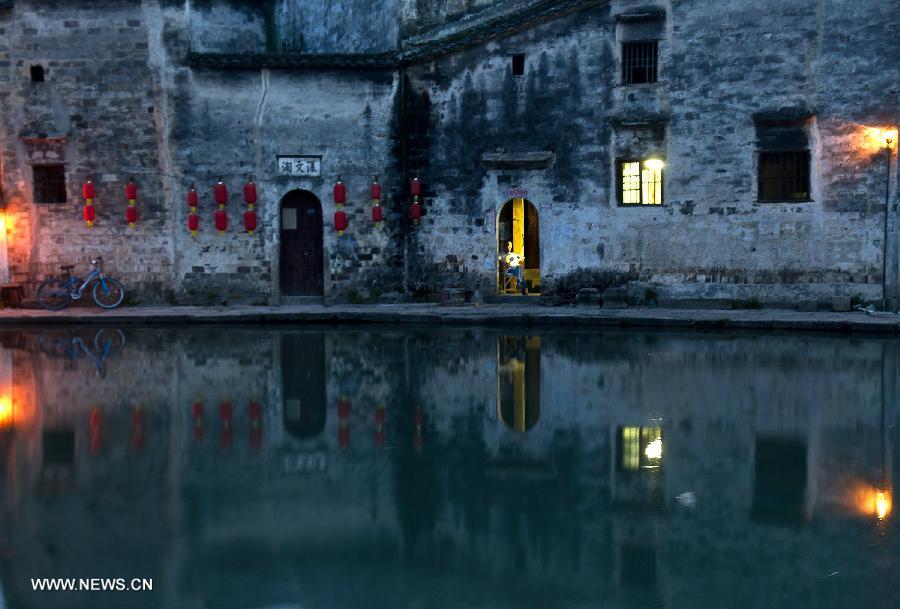 A local resident sits by the door of a building at Hongcun, an ancient village founded in 1131 in Huangshan City, east China's Anhui Province, July 2, 2013. Listed as a world cultural heritage site, the village preserved to a remarkable extent the surviving examples of Anhui-style architecture and traditional lifestyle. (Xinhua/Guo Chen) 