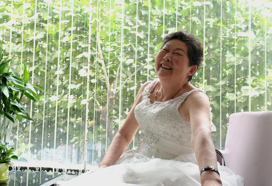 A woman poses in a wedding gown, July 4, 2013. (Xie Chen/Xinhua)
