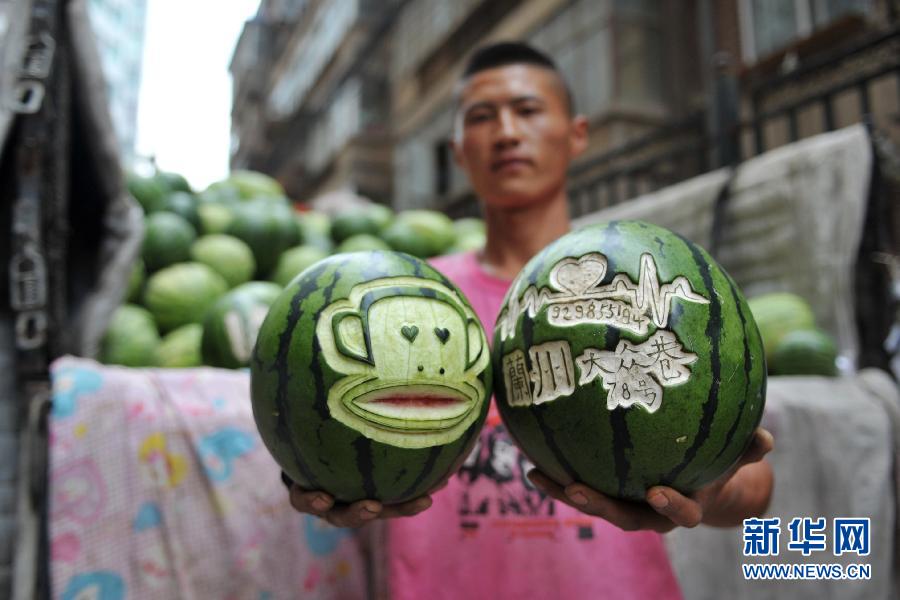 Shen Dongbin shows cartoon figures carved on watermelons at his watermelon stall in northwest China's Lanzhou on July 4, 2013. (Photo/Xinhua)