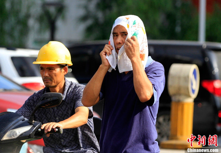 A citizen puts a towel on head to protect from sunshine in Wuhan on July 1, 2013. (CNS/Zhang Chang)