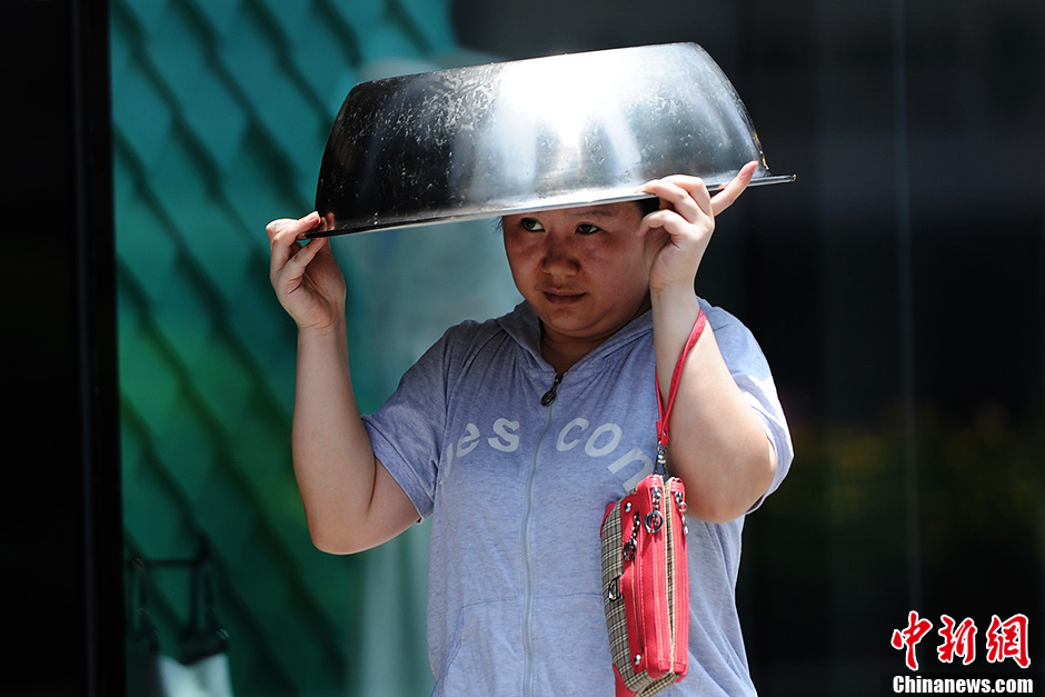A woman uses a pot to protect herself from the sun in Chongqing on June 17, 2013. The temperature of Chongqing reached nearly 40 degrees Celsius on the day. The weather station of Chongqing issued an orange warning of high temperature. (Photo/Chinanews)
