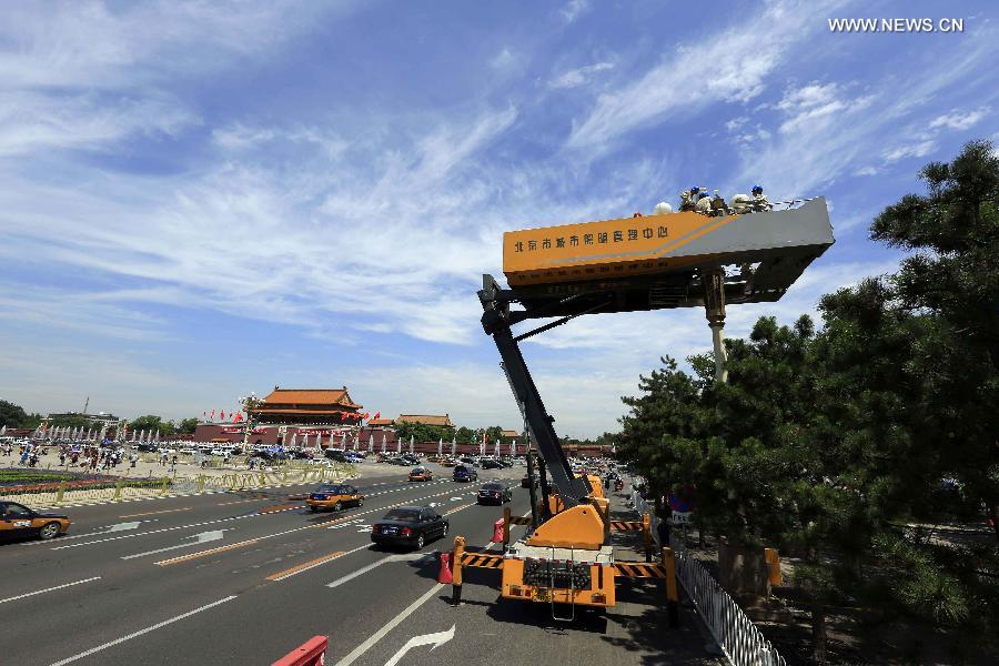 Workers clean and overhaul a lamp during the annual maintenance of city lamps near Tian'anmen Square, Beijing, capital of China, July 4, 2013. (Xinhua/Liu Qinzhuang) 