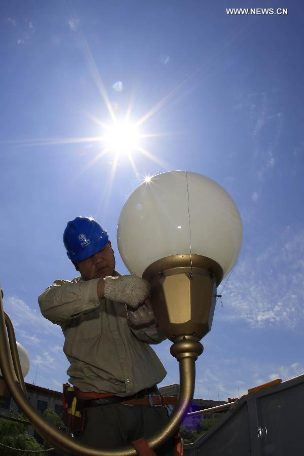 A worker cleans and overhauls a lamp during the annual maintenance of city lamps near Tian'anmen Square, Beijing, capital of China, July 4, 2013. (Xinhua/Liu Qinzhuang) 