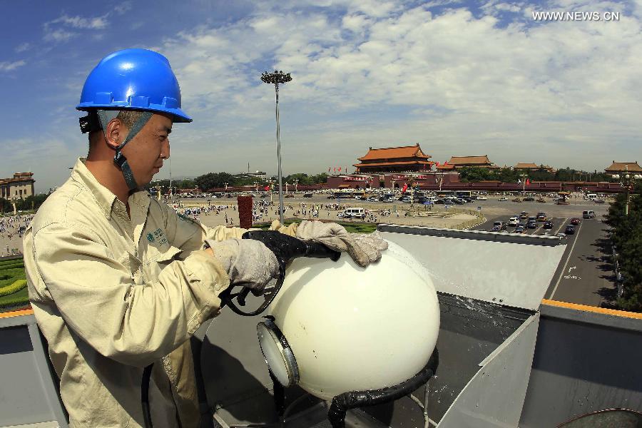 A worker cleans and overhauls a lamp during the annual maintenance of city lamps near Tian'anmen Square, Beijing, capital of China, July 4, 2013. (Xinhua/Liu Qinzhuang) 