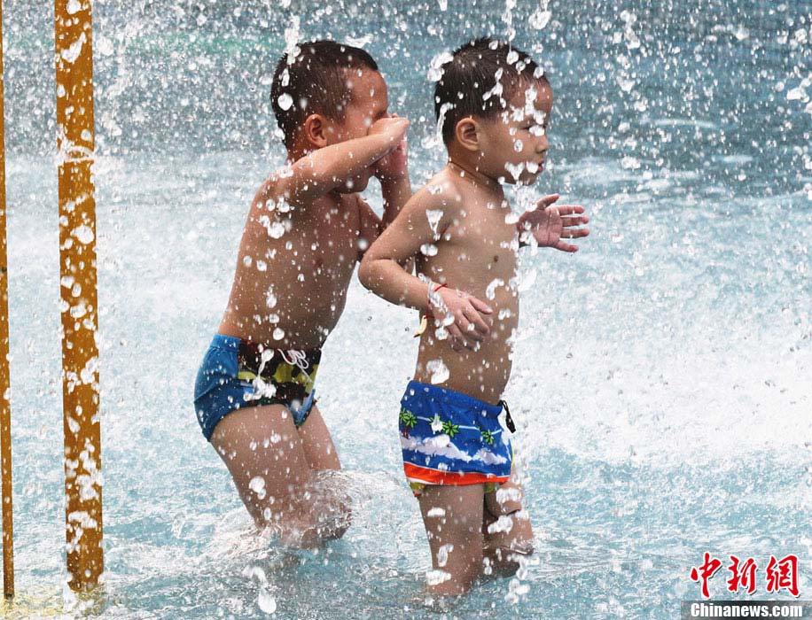 Two children play at the Water World in southwest China’s Chongqing. The weather station of Chongqing issued an orange warning of high temperature as temperatures in some counties of Chongqing reached 39 degree Celsius. (CNS/ Zhou Yi) 