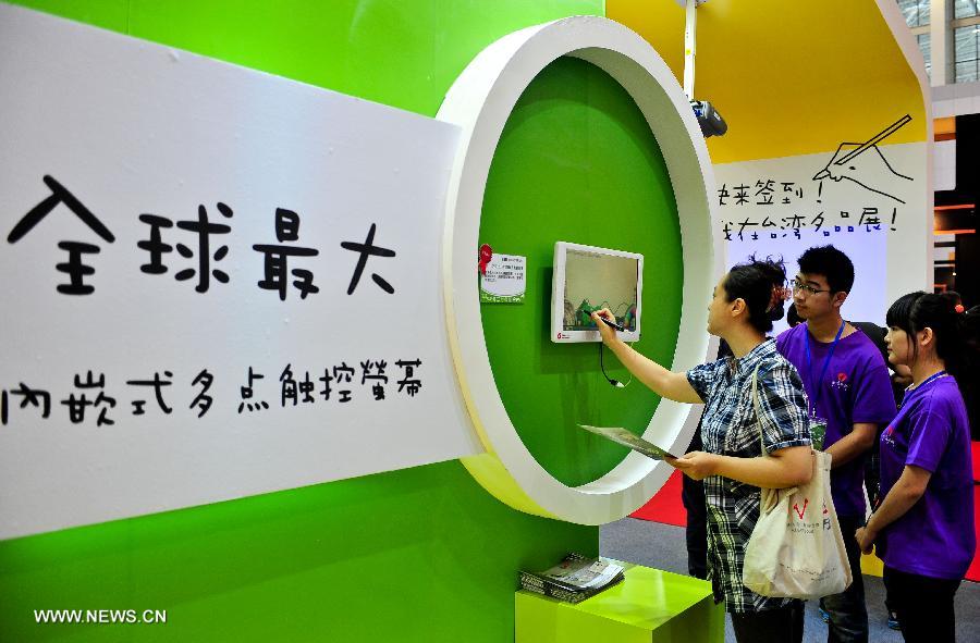 A visitor experiences the largest embedded multi-touch screen during the Taiwan Trade Fair at the Meijiang Convention and Exhibition Center in north China's Tianjian, July 5, 2013. The exhibition will last till July 8, 2013. (Xinhua/Zhai Jianlan)
