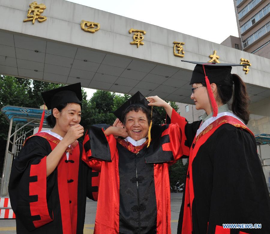 Ph.D. graduates Gao Li (L) and Ji Kun (R) help their tutor Wen Lingying (C) wear her hat in the Fourth Military Medical University in Xi'an, northwest China's Shaanxi Province, July 5, 2013. Altogether 245 Ph.D. students and 575 postgraduate students graduated from the university this year. (Xinhua/Ding Haitao) 