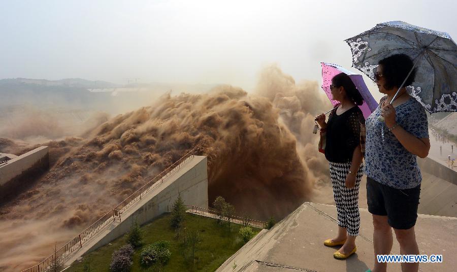 Tourists watch water gushing out from the Xiaolangdi Reservoir on the Yellow River during a sand-washing operation in Luoyang, central China's Henan Province, July 5, 2013. The on-going operation, conducted on Friday, works by discharging water at a volume of 2,600 cubic meters per second from the reservoir to clear up the sediment in the Yellow River , the country's second-longest waterway. Speeding currents would carry tons of sand into the sea. The Yellow River has been plagued by an increasing amount of mud and sand. Each year, the river bed rises as silt deposits build up, slowing the water flow in the lower reaches. (Xinhua/Wang Song)