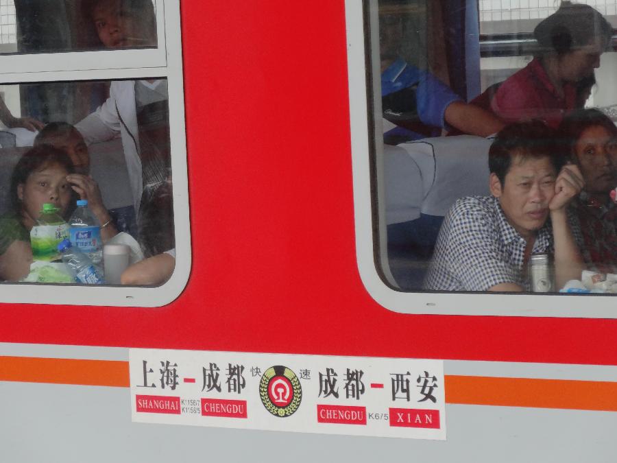 Passengers sit in a train stranded at the Dazhou Railway Station in Dazhou, southwest China's Sichuan Province, July 5, 2013. A new round of heavy rainfall battered Dazhou on Friday morning, making several trains suspended and late. (Xinhua/Deng Liangkui)