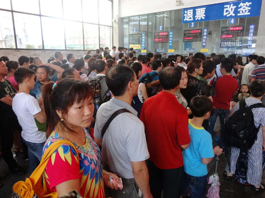 Passengers queue to refund or change tickets at the ticket office of the Dazhou Railway Station in Dazhou, southwest China's Sichuan Province, July 5, 2013. A new round of heavy rainfall battered Dazhou on Friday morning, making several trains suspended and late. (Xinhua/Deng Liangkui)