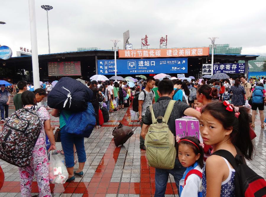 Passengers queue to enter into the Dazhou Railway Station in Dazhou, southwest China's Sichuan Province, July 5, 2013. A new round of heavy rainfall battered Dazhou on Friday morning, making several trains suspended and late. (Xinhua/Deng Liangkui)