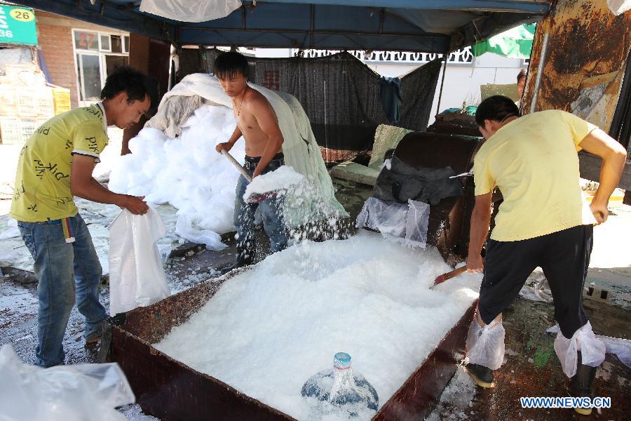 Workers pack the ice powder into bags at the Beijing Xinfadi Agricultural Products Market in Beijing, capital of China, July 5, 2013. With the temperature keeping climbing, sales of ice cubes increased in Beijing in recent days. (Xinhua)