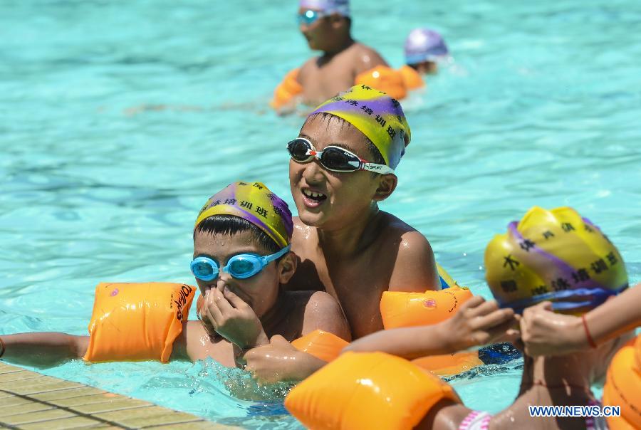 Children take part in a training in a swimming pool in Urumqi, capital of northwest China's Xinjiang Uygur Autonomous Region, July 5, 2013. Some 450,000 pupils and middle school students have started their summer vacation recently. With less homework assigned by the school, they are able to enjoy a relaxing vacation this summer. (Xinhua/Wang Fei) 