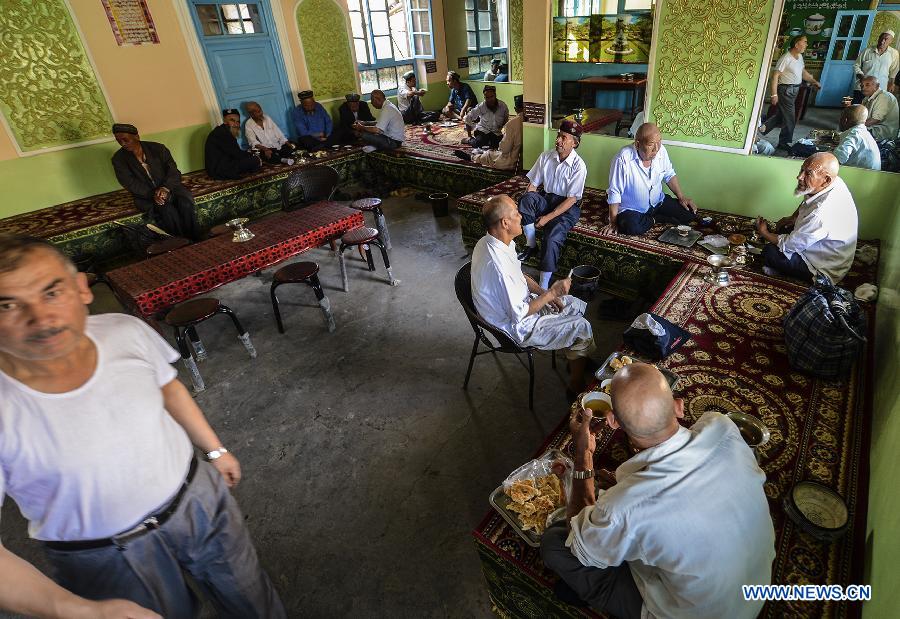 People drink tea and chat with each other at an old teahouse near the Id Kah Square in Kashgar, northwest China's Xinjiang Uygur Autonomous Region, July 5, 2013. With simple decoration, the teahouse is located at the second floor of an old-fishioned building and is favored by the old of Uygur ethnic group. They usually enjoy drinking tea and chatting after every morning prayer. (Xinhua/Shen Qiao)