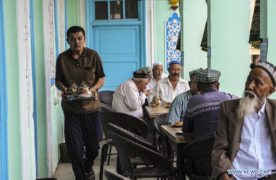 A waiter serves customers with pots of tea at an old teahouse near the Id Kah Square in Kashgar, northwest China's Xinjiang Uygur Autonomous Region, July 5, 2013. With simple decoration, the teahouse is located at the second floor of an old-fishioned building and is favored by the old of Uygur ethnic group. They usually enjoy drinking tea and chatting after every morning prayer. (Xinhua/Shen Qiao)