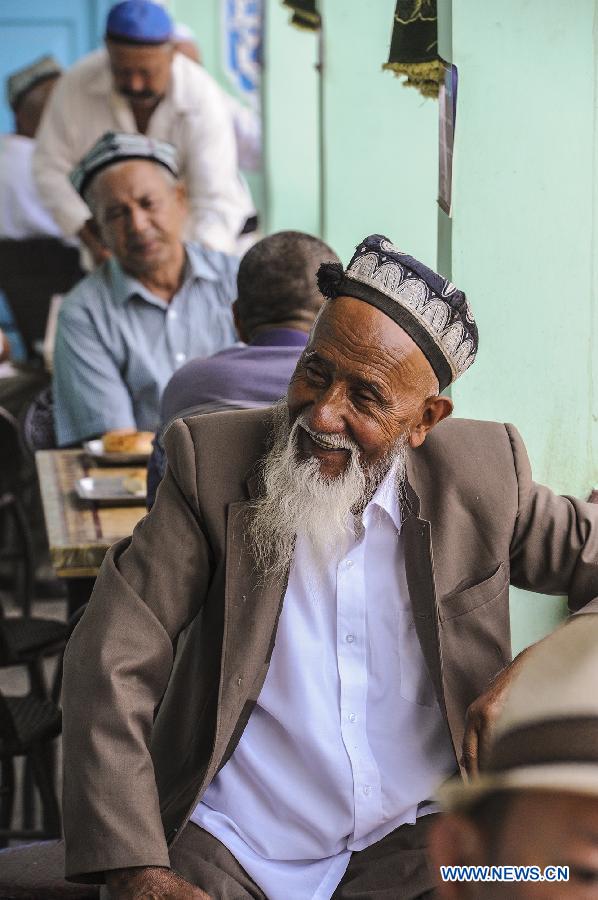 An old resident of Uygur ethnic group reacts while sitting at an old teahouse near the Id Kah Square in Kashgar, northwest China's Xinjiang Uygur Autonomous Region, July 5, 2013. With simple decoration, the teahouse is located at the second floor of an old-fishioned building and is favored by the old of Uygur ethnic group. They usually enjoy drinking tea and chatting after every morning prayer. (Xinhua/Shen Qiao)