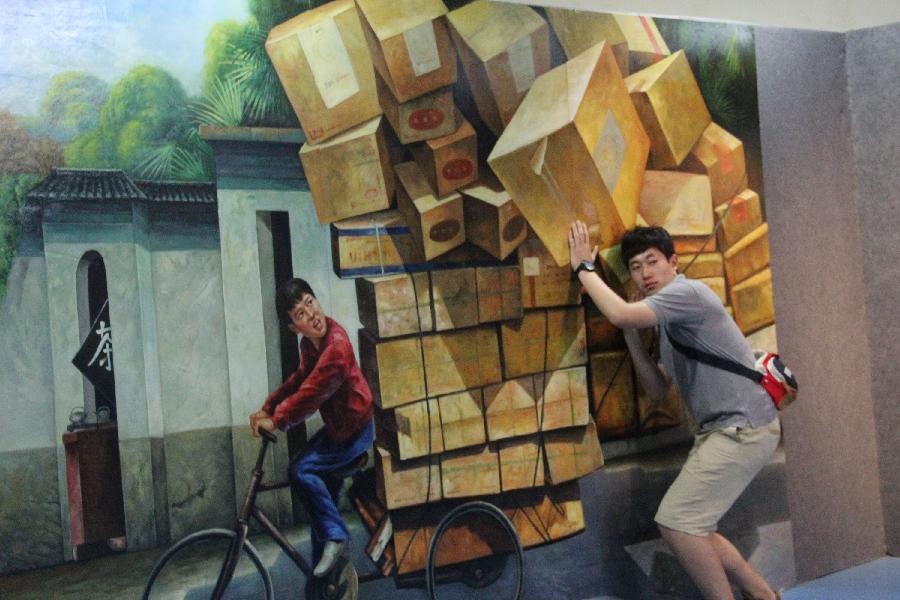 A man poses for photos with a 3D painting in a museum in Qingdao, east China's Shandong Province, July 5, 2013. A 3D magic art show was opened here on Friday, in which about 40 3D paintings attracted many students who were in their summer vacations.(Xinhua/Huang Jiexian)