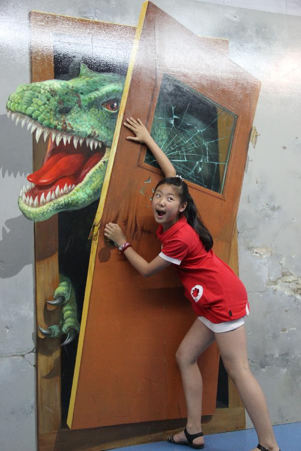 A girl poses for photos with a 3D painting in a museum in Qingdao, east China's Shandong Province, July 5, 2013. A 3D magic art show was opened here on Friday, in which about 40 3D paintings attracted many students who were in their summer vacations.(Xinhua/Huang Jiexian)