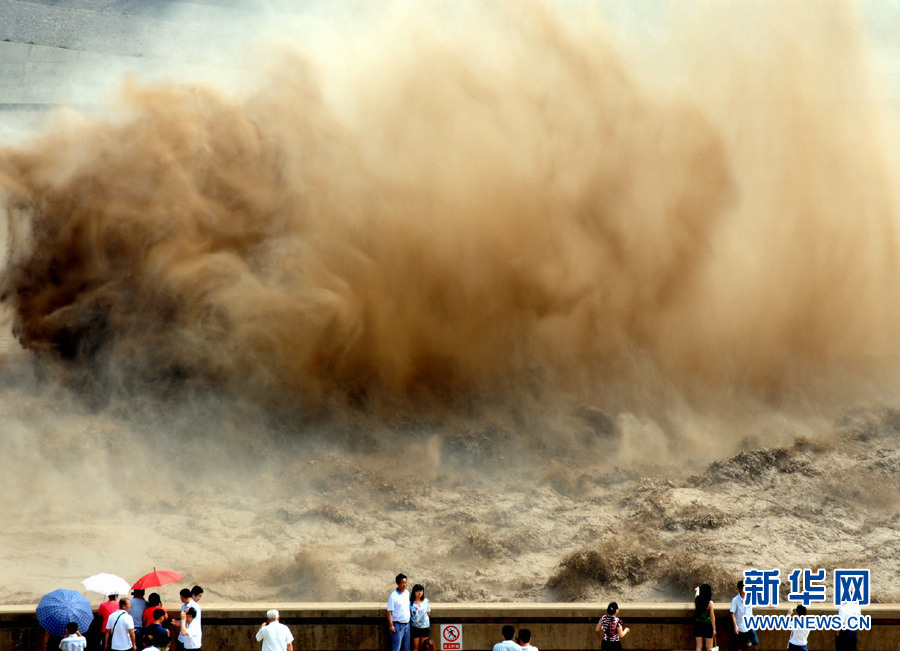 Tourists watch water gushing out from the Xiaolangdi Reservoir on the Yellow River during a sand-washing operation in Luoyang, central China's Henan Province, July 5, 2013.  (Xinhua/Miao Qiu Nao)