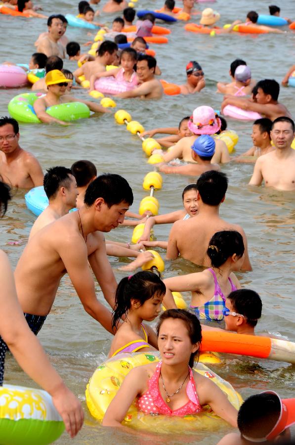 Tourists enjoy coolness at the Dashawan bathing beach in Lianyungang, east China's Jiangsu Province, July 6, 2013. The beach entered its tourism peak season with the rising temperature. (Xinhua/Wang Chun) 