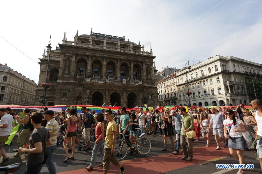 Participants carrying a rainbow flag, symbol of the LGBTQ movement, walk across the city during the Gay Pride Parade in Budapest, Hungary on July 6, 2013. (Xinhua/Attila Volgyi)   