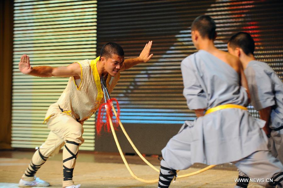 A performer of the Yandong Shaolin Kungfu troupe makes double spears crooked by resisting spear heads during a performance held at the Worker's Cultural Palace, Taiyuan, capital of north China's Shanxi Province, July 6, 2013. The martial art troupe have their performers trained in the renowned Shaolin Temple, and staged performances worldwide in the hope of promoting Shaolin-style martial arts and Chinese culture. (Xinhua/Fan Minda)