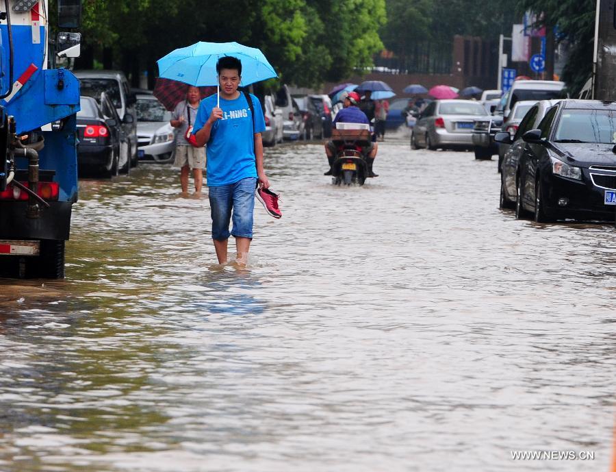 A man walks on a flooded road in Wuchang District of Wuhan, capital of central China's Hubei Province, July 7, 2013. Wuhan was hit by the heaviest rainstorm in five years from Saturday to Sunday. The local meteorologic center has issued red alert for rainstorm for many times in sequence. (Xinhua/Xiao Yijiu) 