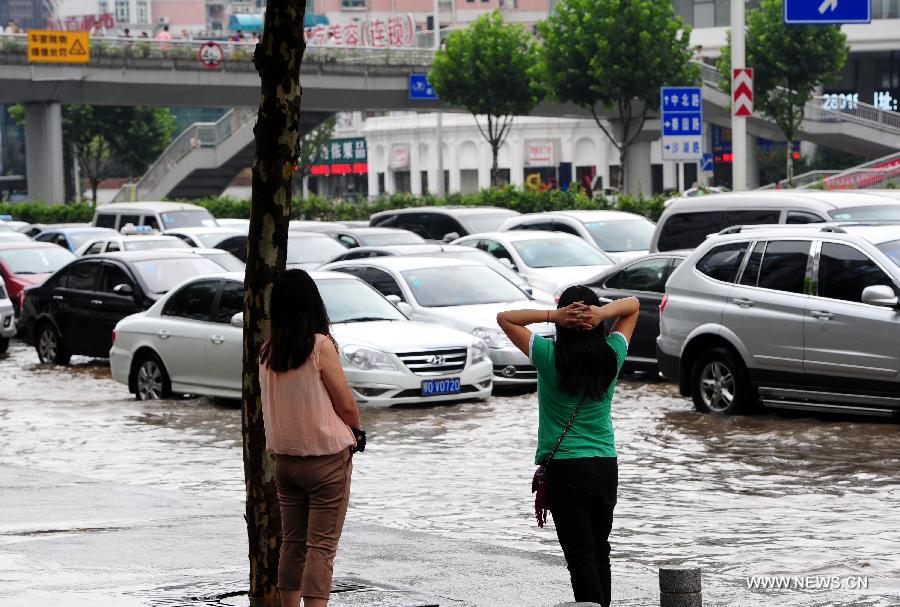 People watch cars driving on a flooded road in Wuchang District of Wuhan, capital of central China's Hubei Province, July 7, 2013. Wuhan was hit by the heaviest rainstorm in five years from Saturday to Sunday. The local meteorologic center has issued red alert for rainstorm for many times in sequence. (Xinhua/Xiao Yijiu) 