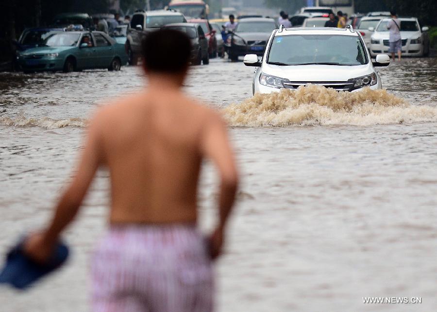 A car drives on a flooded road in Wuhan, capital of central China's Hubei Province, July 7, 2013. Wuhan was hit by the heaviest rainstorm in five years from Saturday to Sunday. The local meteorologic center has issued red alert for rainstorm for many times in sequence. (Xinhua/Cheng Min) 