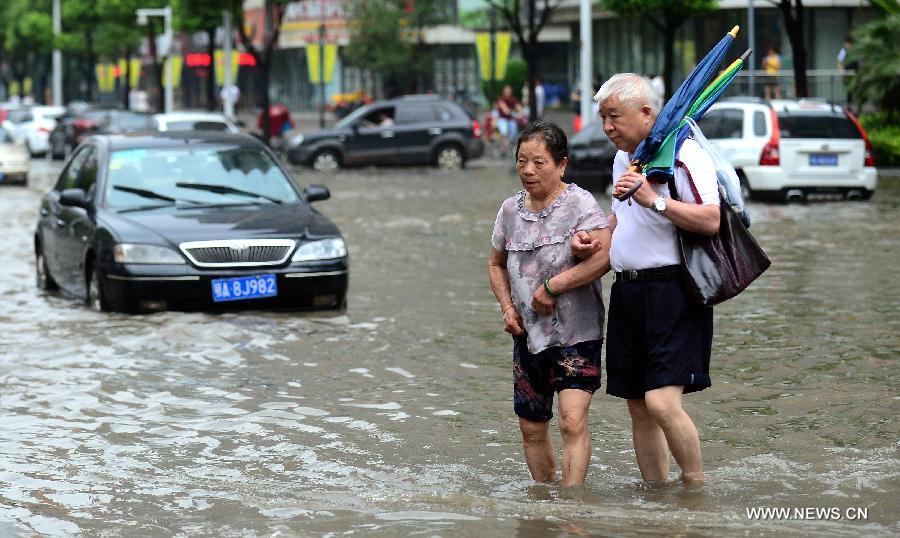 Two elders walk across a flooded road in Wuhan, capital of central China's Hubei Province, July 7, 2013. Wuhan was hit by the heaviest rainstorm in five years from Saturday to Sunday. The local meteorologic center has issued red alert for rainstorm for many times in sequence. (Xinhua/Cheng Min) 