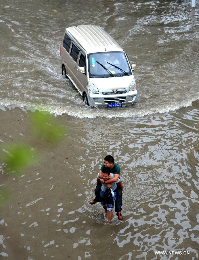 A man carrying his friend walks in the flood water in Wuhan, capital of central China's Hubei Province, July 7, 2013. Wuhan was hit by the heaviest rainstorm in five years from Saturday to Sunday. The local meteorologic center has issued red alert for rainstorm for many times in sequence. (Xinhua/Cheng Min) 
