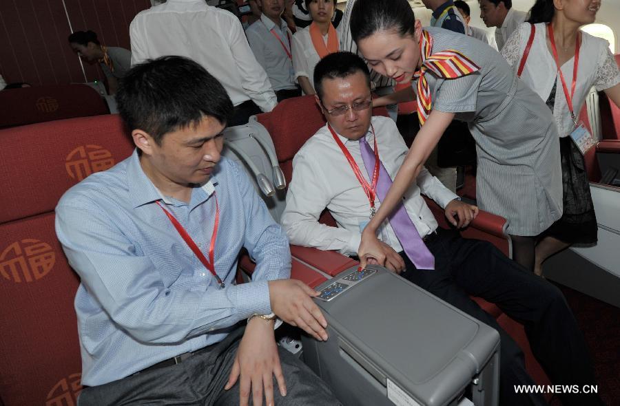 A crew member demonstrates how to adjust seats to visitors on a Boeing 787 Dreamliner during a ceremony at the Haikou Meilan International Airport in Haikou, capital of south China's island of Hainan Province, July 7, 2013. Haian Airlines held a ceremony here to welcome the arrival of its first Boeing 787 Dreamliner. Mou Wei, vice president of Hainan Airlines, said on July 4 that the first 213-seat Dreamliner will serve the domestic route between Beijing and Haikou, capital of south China's Hainan Province, with 36 seats reserved for business class and 177 for economy. (Xinhua/Zhao Yingquan)
