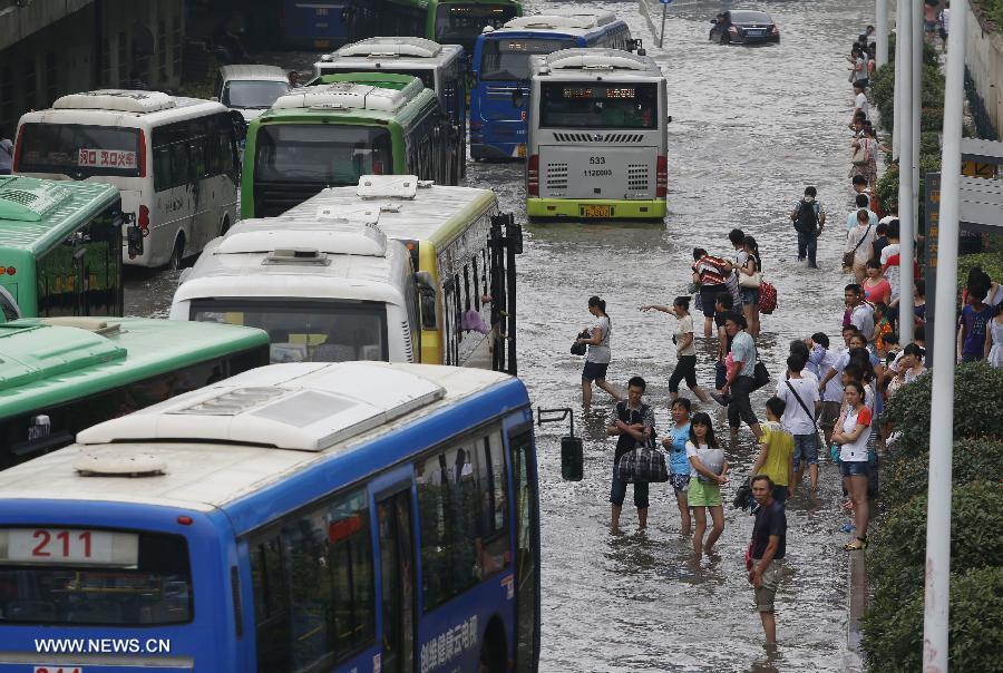People wait for bus on a flooded road in Wuhan, capital of central China's Hubei Province, July 7, 2013. Wuhan was hit by the heaviest rainstorm in five years from Saturday to Sunday. The local meteorologic center has issued red alerts for rainstorm for many times in sequence. (Xinhua)