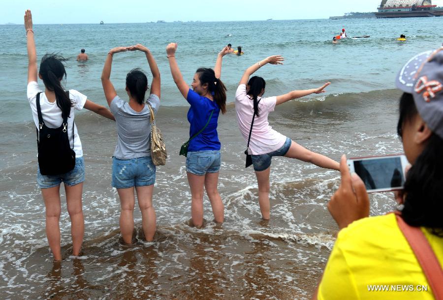 Tourists pose their bodies into the "love" shape at a bathing beach in Qingdao, a coastal city of east China's Shandong Province, July 7, 2013. (Xinhua/Li Ziheng)