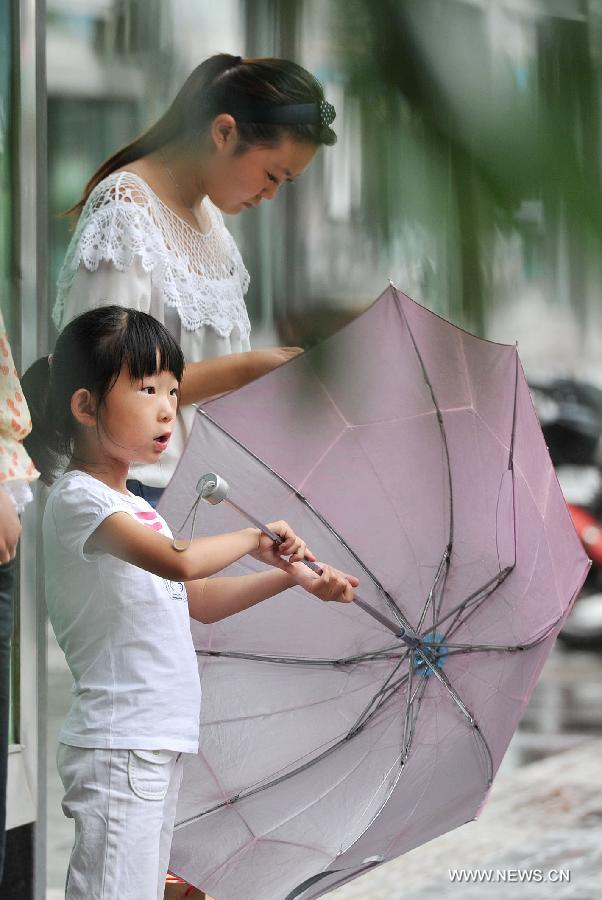 A little girl waits for the bus in rain in Yinchuan, capital of northwest China's Ningxia Hui Autonomous Region, July 7, 2013. Xiaoshu (Lesser Heat), the 11th of the 24 solar terms in the Chinese Lunar Calendar which means the beginning of hot summer, fell on Saturday. Rainfall brought cool to Yinchuan on Xiaoshu. (Xinhua/Peng Zhaozhi)