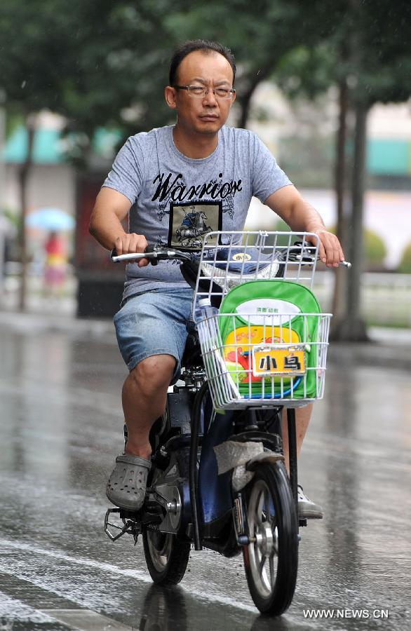 A man rides in rain in Yinchuan, capital of northwest China's Ningxia Hui Autonomous Region, July 7, 2013. Xiaoshu (Lesser Heat), the 11th of the 24 solar terms in the Chinese Lunar Calendar which means the beginning of hot summer, fell on Saturday. Rainfall brought cool to Yinchuan on Xiaoshu. (Xinhua/Peng Zhaozhi)