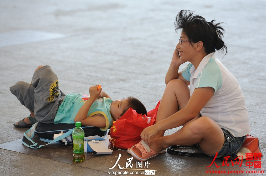 A child accompanied by adult waits for the train at the square of Fuyang Railway Station, east China's Anhui province, July 2, 2013. (photo/vip.people.com.cn)