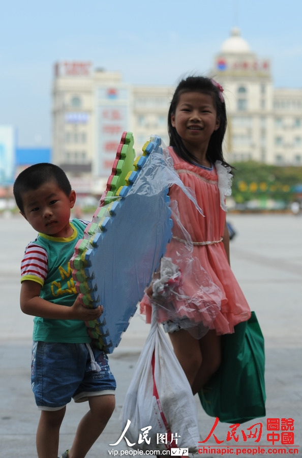 Two children accompanied by adults take the train to spend holidays with their parents working in cities at Fuyang Railway Station, east China's Anhui province, July 2, 2013. (photo/vip.people.com.cn)