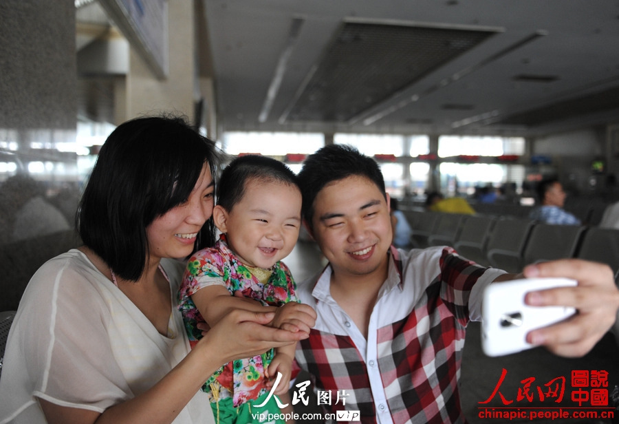 A family poses for photos in the waiting room of Fuyang Railway Station on July 1, 2013. (photo/vip.people.com.cn)